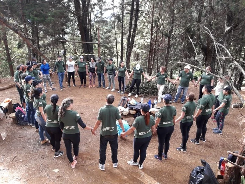 Personas reunidas en círculo entre árboles durante una actividad grupal