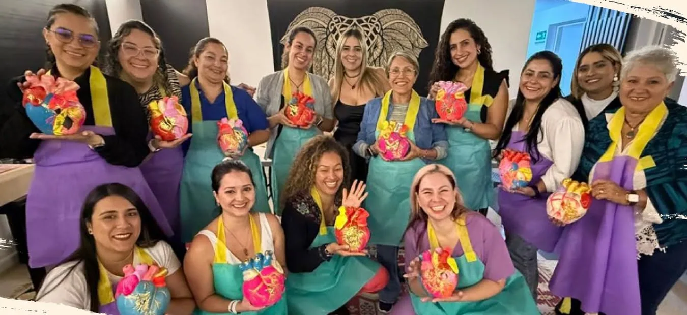 Mujeres sostienen piezas artísticas durante una actividad grupal.